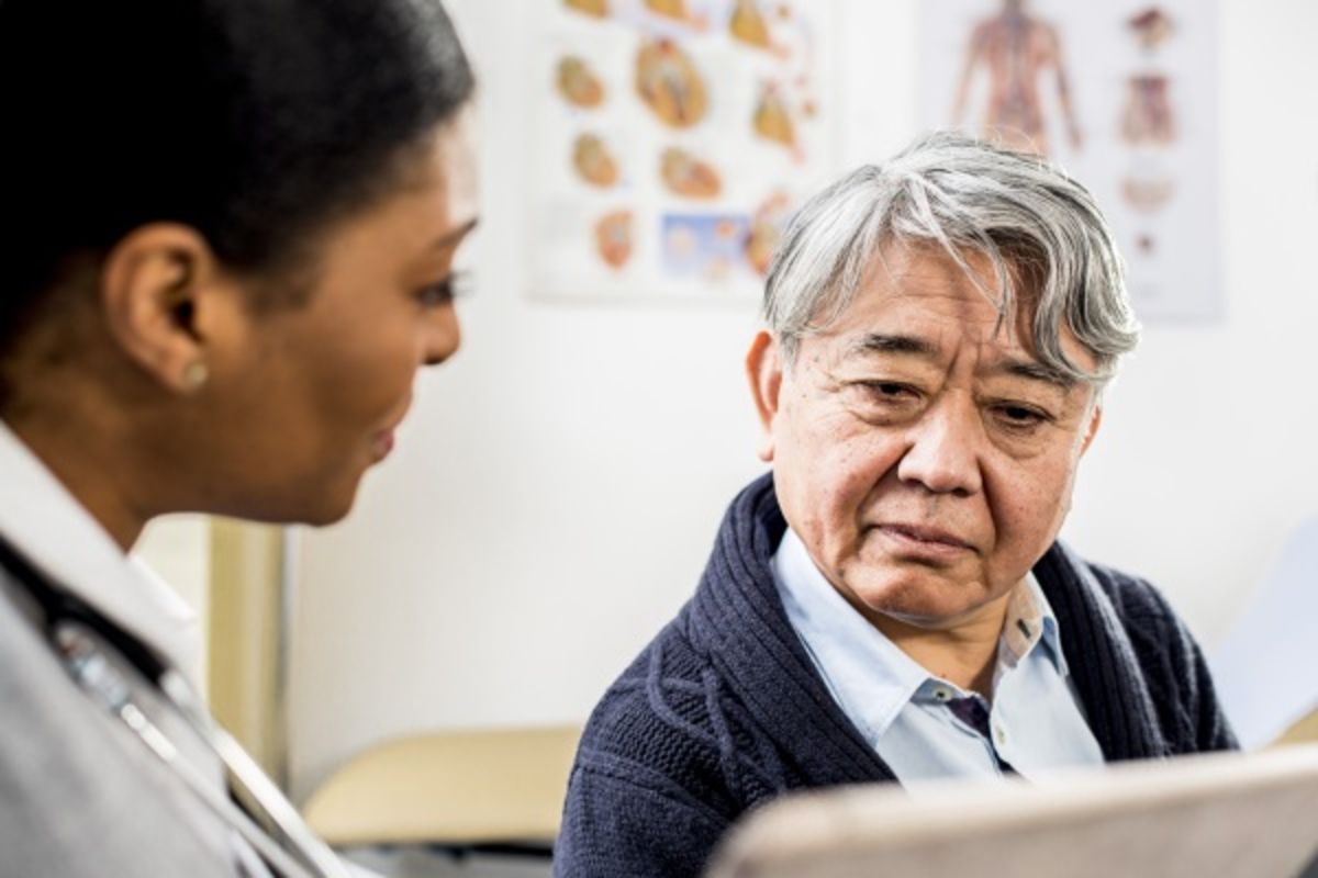 Female HCP and male patient review information on a digital tablet.